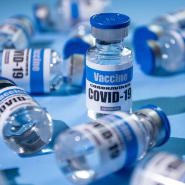 Glass vials for Covid-19 vaccine on blue background. Group of Coronavirus vaccine bottles.