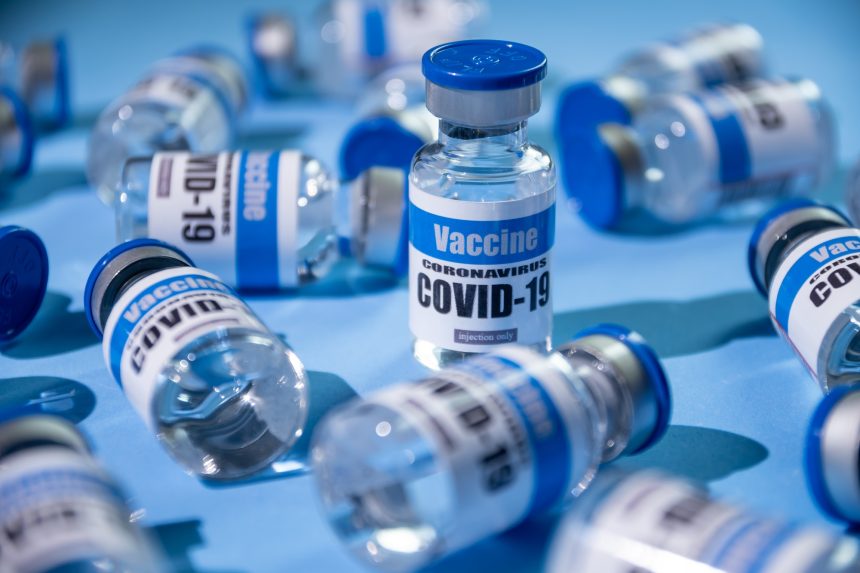 Glass vials for Covid-19 vaccine on blue background. Group of Coronavirus vaccine bottles.